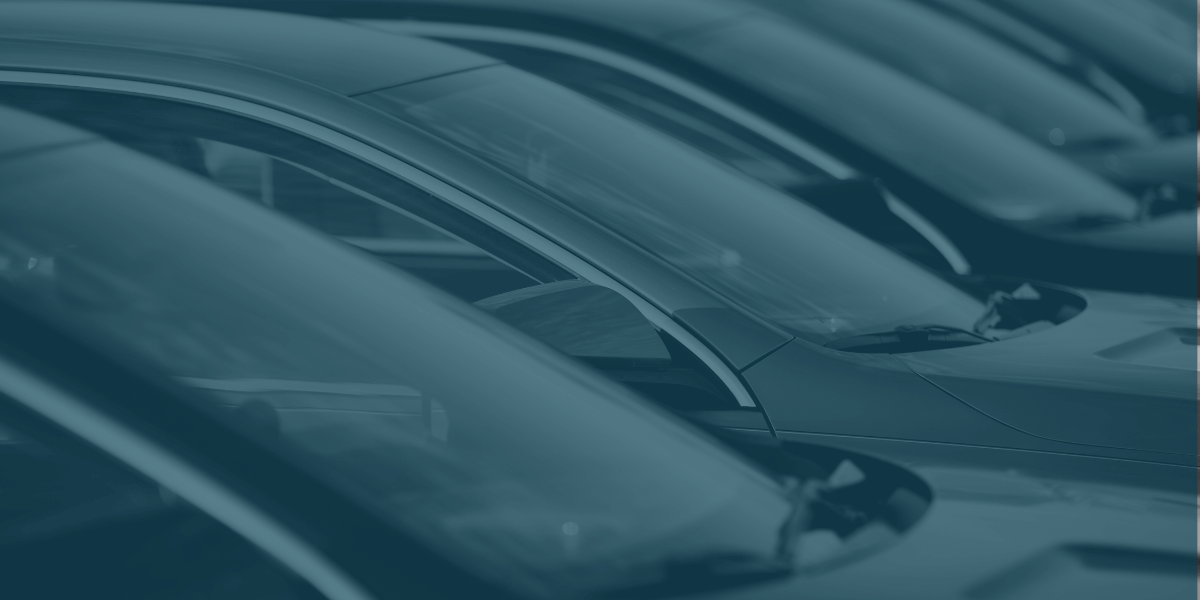 Row of parked vehicles highlighting windshields and hoods in a dealership lot.