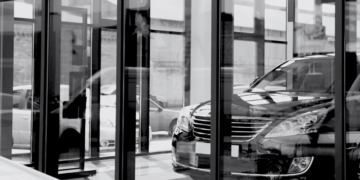Close up view of an auto dealership front lobby view of a car through glass windows